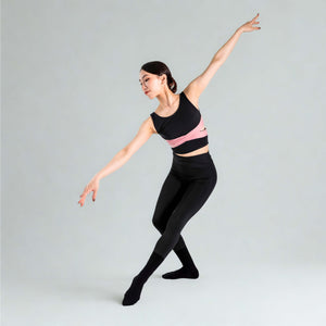 Model performing a graceful ballet-inspired pose wearing YOGASANA Aurora Ballerina Dual Tone Leggings in black with pink waistband.