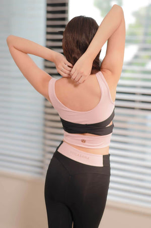 Model wearing the Aurora Ballerina Dual Tone Cross Back Sports Bra in Daylight Paris pink and black, back view showing the cross-strap design.