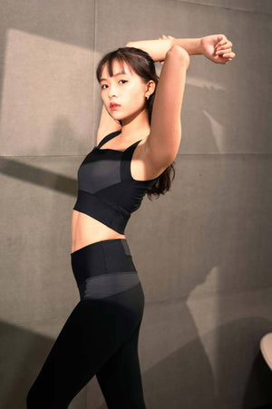 Model stretching in YOGASANA Brandi Minimalist Leggings in Midnight New York black, featuring ergonomic waistband and tonal grey detail.