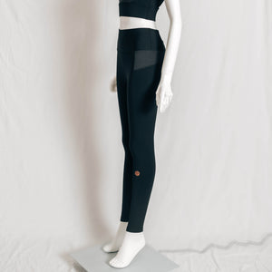 Side mannequin view of YOGASANA Brandi Minimalist Leggings in Midnight New York black, highlighting the sleek contour lines, contrast grey waistband, and minimalist ankle logo.