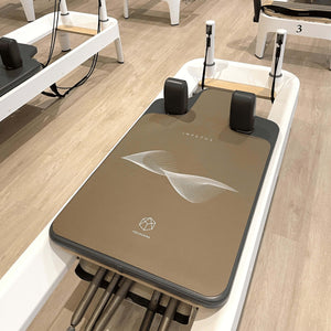 IMPETUS 2mm Pilates Reformer Mat - Desert Edition placed on white reformer machine in studio