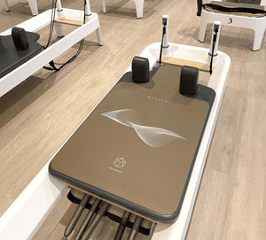 IMPETUS 2mm Pilates Reformer Mat - Desert Edition placed on white reformer machine in studio