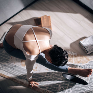Model in forward bend pose using yoga wheel on YOGASANA Urban Portrait 1mm Soft-touch Yoga Mat – Midnight New York, emphasising elegant posture and mindful movement.