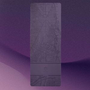 Flat lay of YOGASANA Glamorous Barcelona Urban Sketch Yoga Mat with city map design and gradient purple tones.