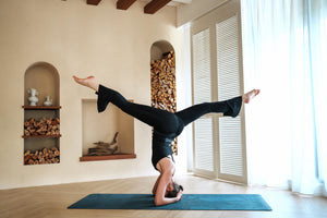 Model wearing YOGASANA Cassie Performance Flared Leggings in Midnight New York black performing headstand pose, showcasing flare-leg flexibility and sculpting support fit.