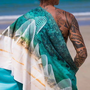 Yogasana Gradient Balance yoga towel – back view of model wrapped in the towel on a sunny beach, showing double-sided pattern.