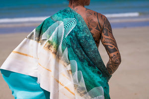 Yogasana Gradient Balance yoga towel – back view of model wrapped in the towel on a sunny beach, showing double-sided pattern.