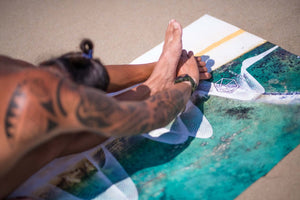 Yogasana Gradient Balance yoga towel – close-up of ocean-inspired print during beach stretch exercise.