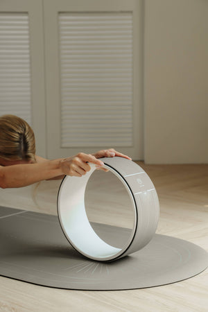Woman rolling forward on Lumiere Sundial Yoga Wheel – Dune (Silver Pattern Edition), focusing on alignment and mindful movement.