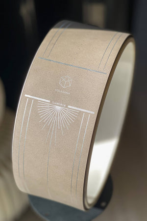 Close-up of Lumiere Sundial Yoga Wheel – Dune (Silver Pattern Edition) featuring the YOGASANA logo and signature sunray pattern in silver on a matte dune surface.