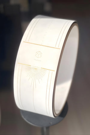 Close-up of Lumiere Sundial Yoga Wheel – White (Golden Pattern Edition) featuring the YOGASANA logo and golden sunburst design under natural light.