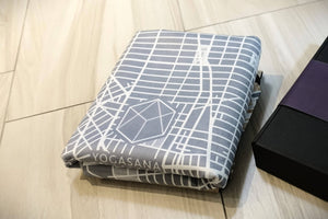 Folded YOGASANA Urban Portrait 1mm Soft-touch Yoga Mat – Midnight New York with signature geometric logo, showing lightweight and compact travel-friendly design.