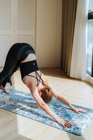 Model practicing downward dog on YOGASANA Urban Portrait 4mm Natural Rubber Yoga Mat – Misty London, revealing the elegant London city map pattern and strong traction surface.