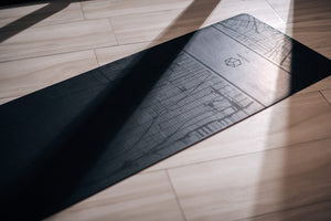 Close-up of the Urban Sketch Natural Rubber Yoga Mat – Midnight New York, with soft sunlight highlighting the map texture and logo.