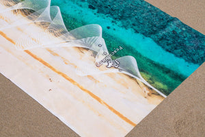 Close-up of Yogasana landscape yoga towel on the sand, featuring ocean-inspired design