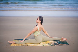 Woman practicing yoga splits on Yogasana landscape yoga towel by the ocean