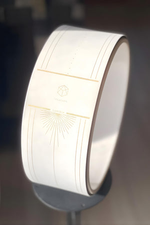 Detailed view of Yogasana Lumiere Sundial Wheel – golden logo and alignment lines on white base.