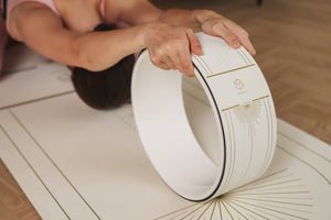Woman stretching with YOGASANA Lumière yoga wheel, designed for balance, alignment, and mindful movement